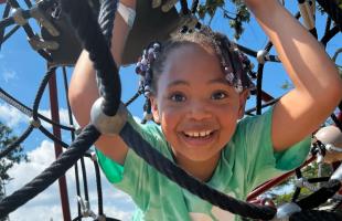 Child wearing a YMCA summer camp shirt plays on a playground
