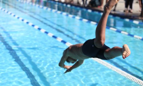 person jumping into lap pool