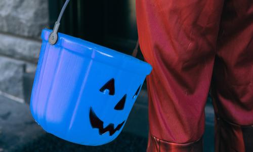 Child holds blue pale for trick-or-treat