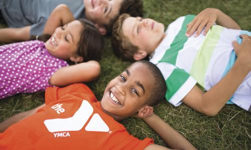 Summer camp kids lay on the grass