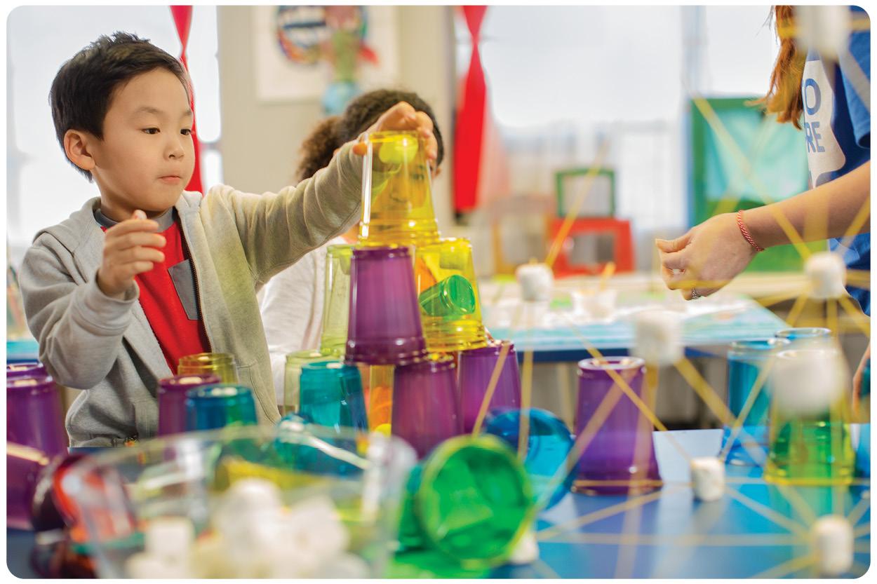 Children doing a STEM activity together with a staff member helping 