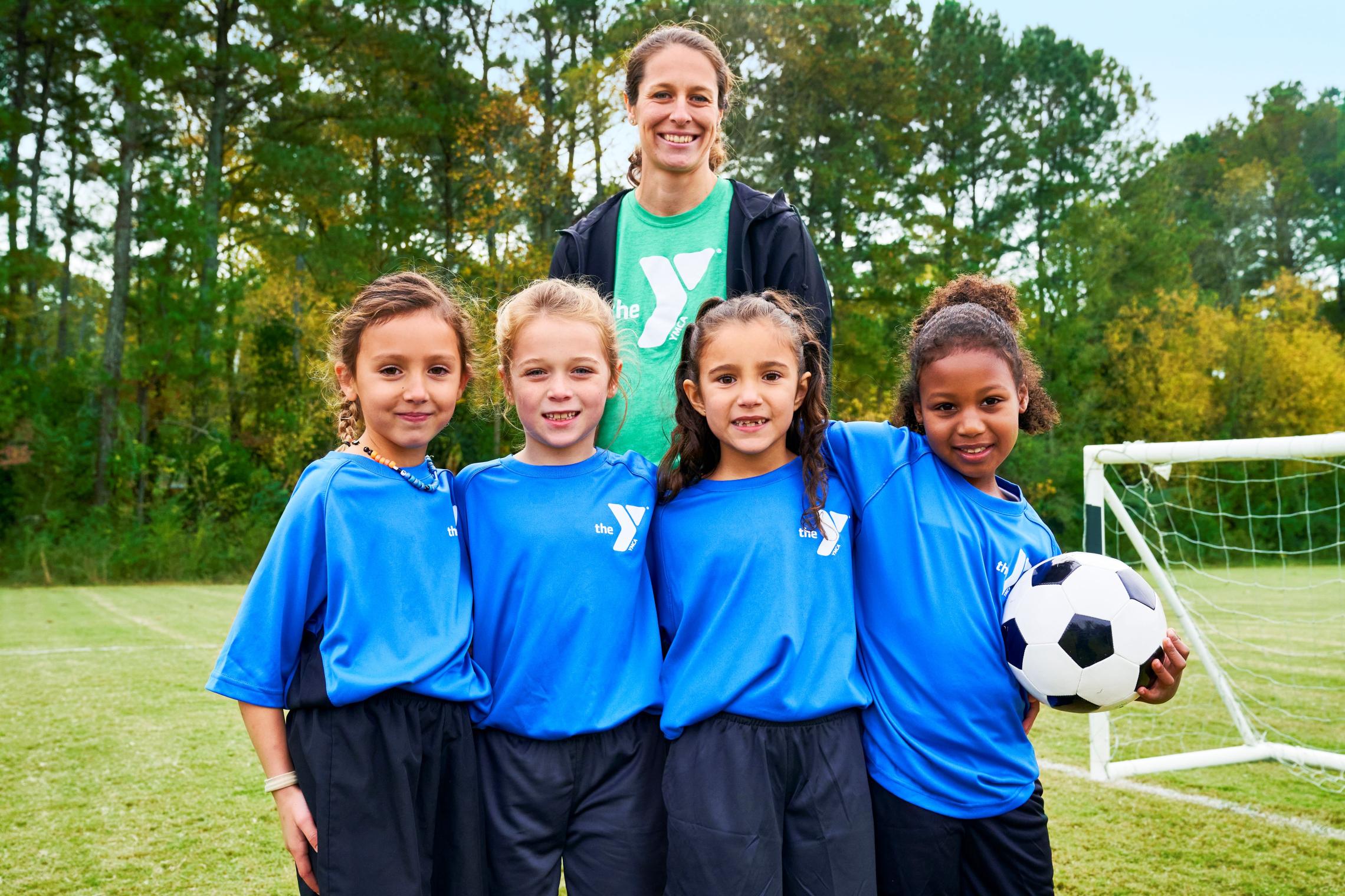 Coach with 4 girls playing soccer on a team