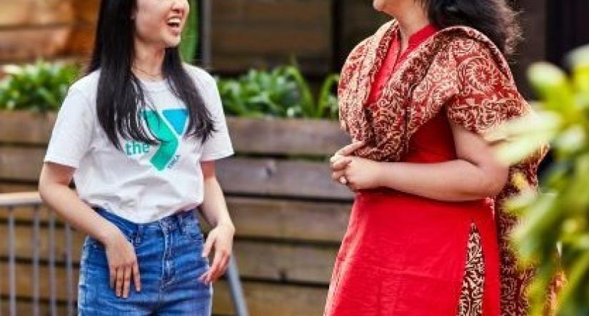 2 women laughing, one in Y t-shirt and jeans, other woman wearing traditional culture-specific clothing