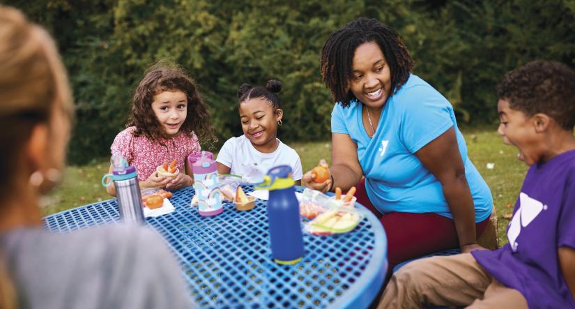 Campers and counselor at lunch table outside