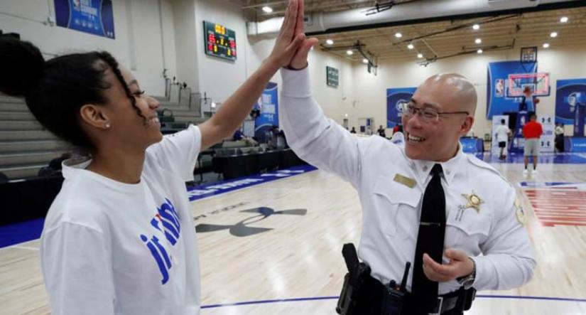 Young girl and police officer high five in a basketball court