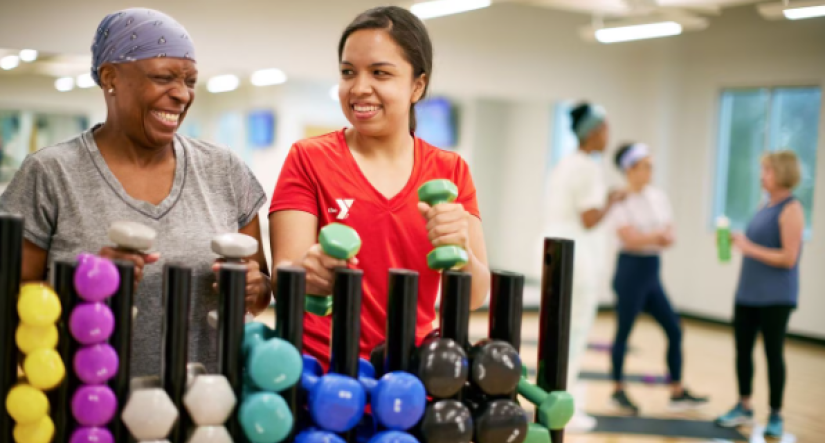 Y Staff and older member grabbing weights for exercise class