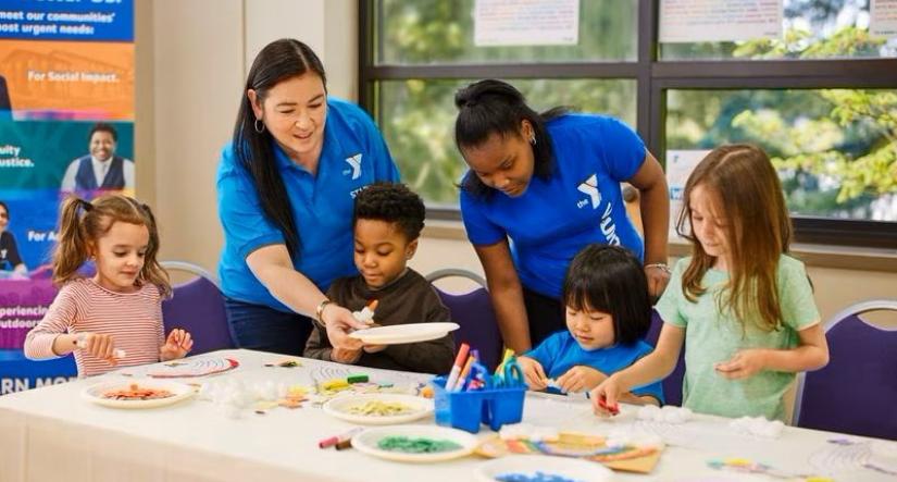 Female YMCA staff in blue shirts teaching children