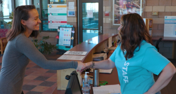 Image of a member checking in at the front desk.